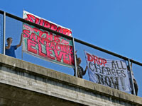 Banners on Highway One: "Support The Santa Cruz Eleven" and "Drop All Charges Now!"