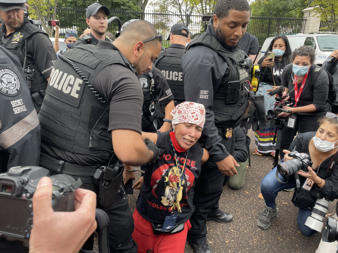 An Indigenous environmental activist is beign deatained by the Secret Service as journalists record and document the event.