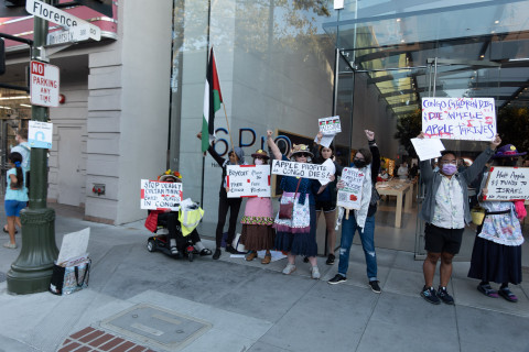 women in aprons and a man with Palestinian flag