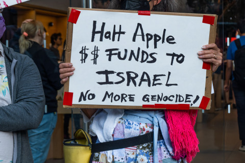 Woman in apron with sign: Halt Apple Funds to Israel