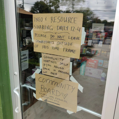 A photo of Firestorm Books' front door. Cardboard signs taped to the glass.