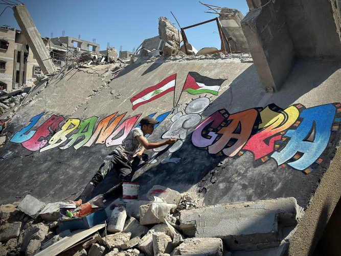 Jamil al-Baz paints a mural in solidarity with Lebanon on rubble in Khan Younis, September 2024.