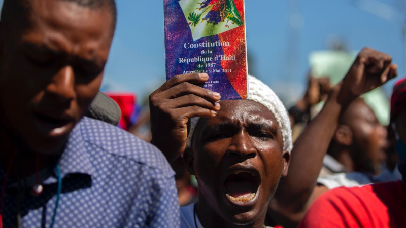 Haitian protester holding up the Haitian constitution