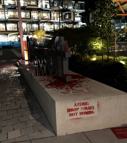 Side view of Microsoft sign with spray paint that reads "Azure: drop israel not bombs" on the side of the sign platform