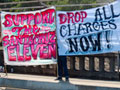 Banners on Highway One: "Support The Santa Cruz Eleven" and "Drop All Charges Now!"